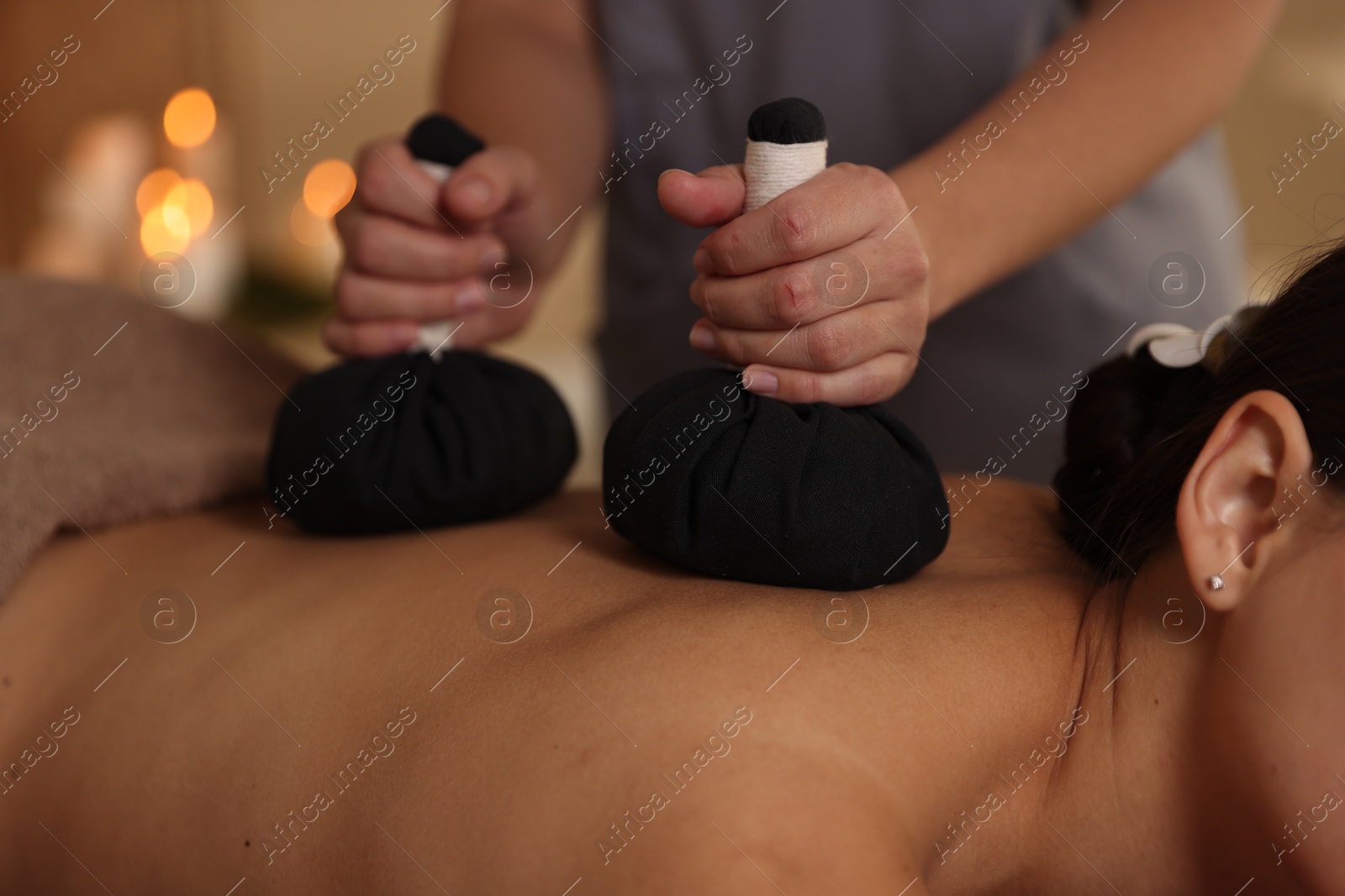 Photo of Woman receiving back massage with herbal bags in spa salon, closeup