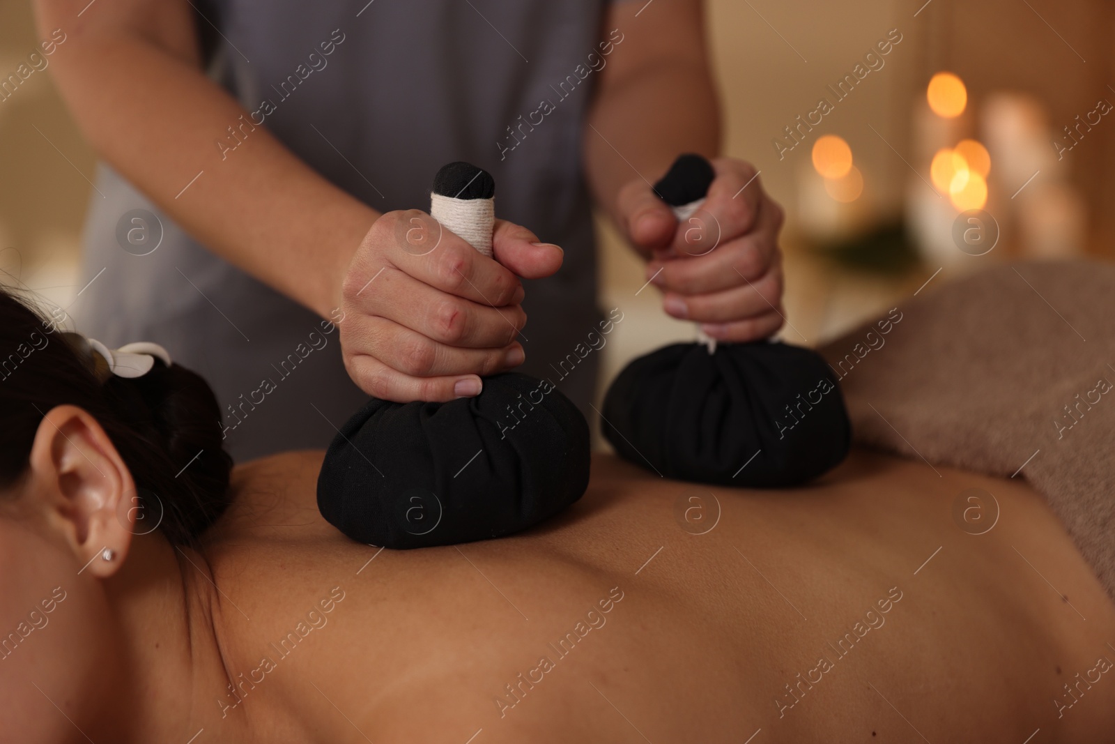 Photo of Woman receiving back massage with herbal bags in spa salon, closeup