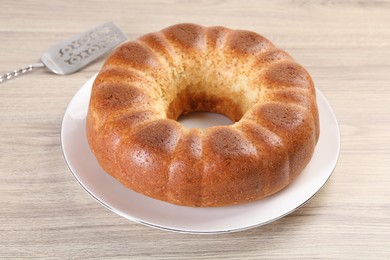 Photo of Freshly baked sponge cake and server on wooden table, closeup