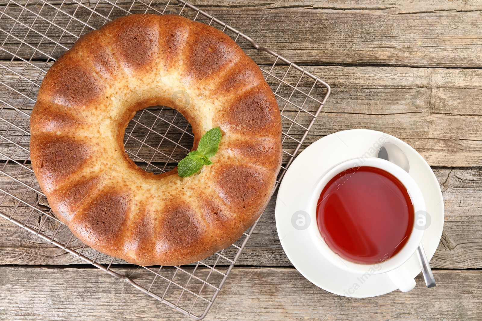 Photo of Freshly baked sponge cake and tea on wooden table, top view