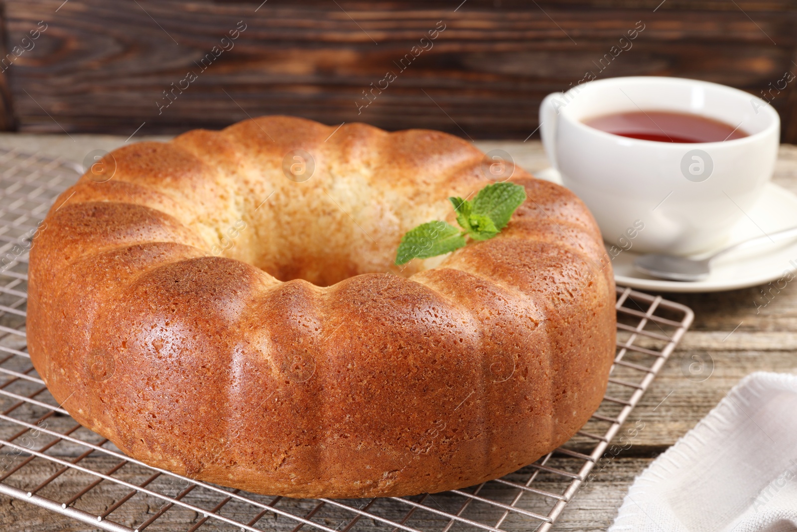 Photo of Freshly baked sponge cake and tea on wooden table, closeup