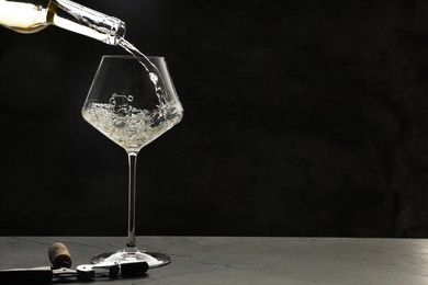 Photo of Pouring white wine into glass at grey table, space for text