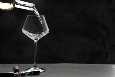 Photo of Pouring white wine into glass at grey table, space for text