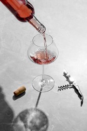 Photo of Pouring rose wine into glass at grey marble table