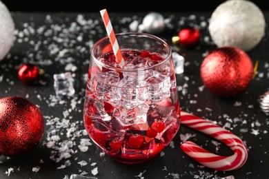 Photo of Tasty Christmas cocktail in glass, ice and decor on black table, closeup