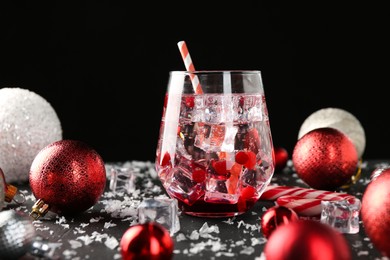 Photo of Tasty Christmas cocktail in glass, ice and decor on black table, closeup