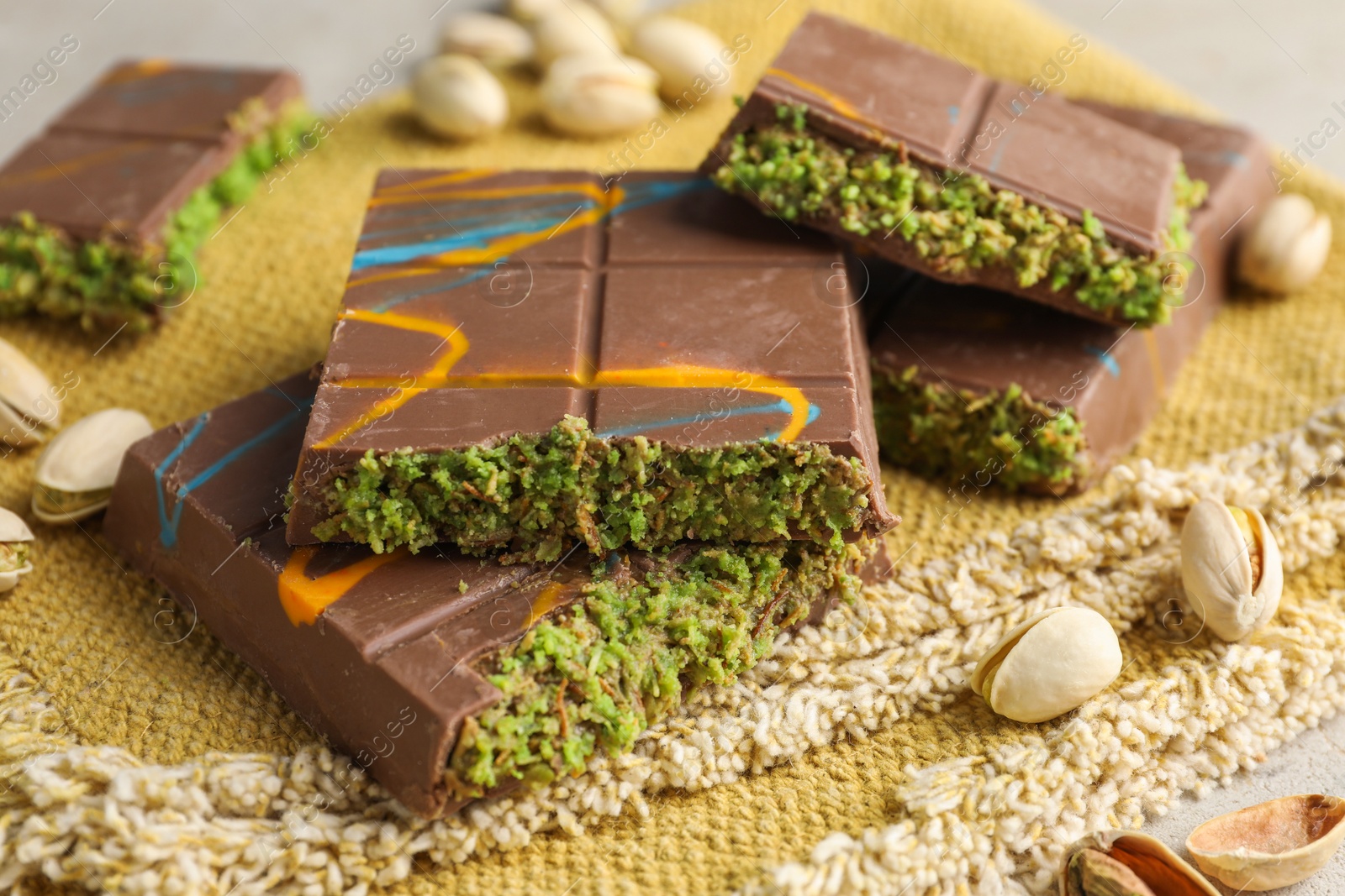 Photo of Pieces of Dubai chocolate bar with pistachios and knafeh on table, closeup