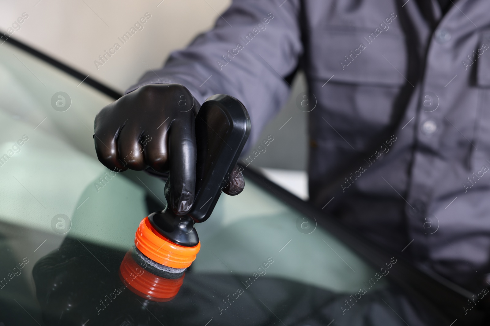 Photo of Man polishing car windshield indoors, closeup view