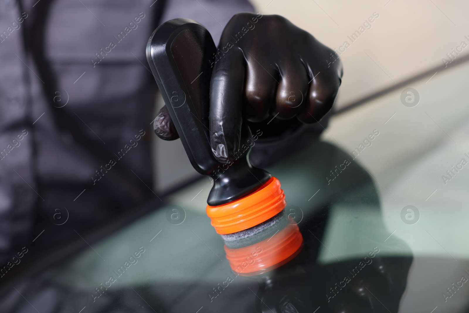 Photo of Man polishing car windshield indoors, closeup view