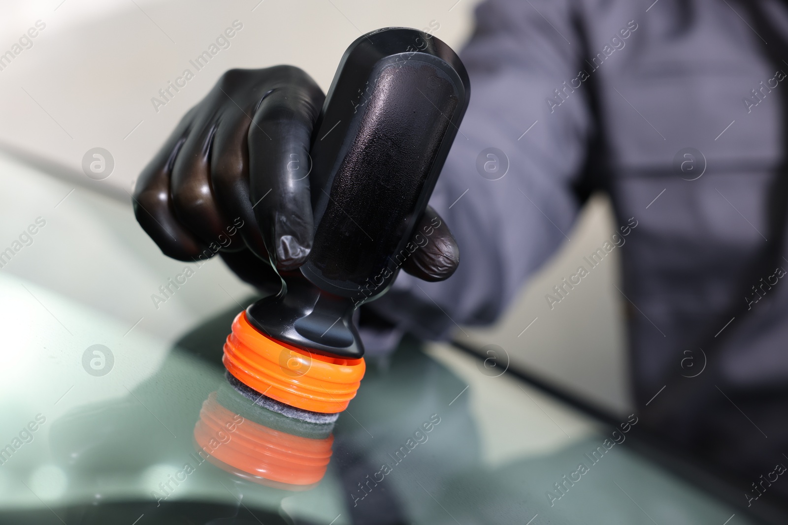 Photo of Man polishing car windshield indoors, closeup view