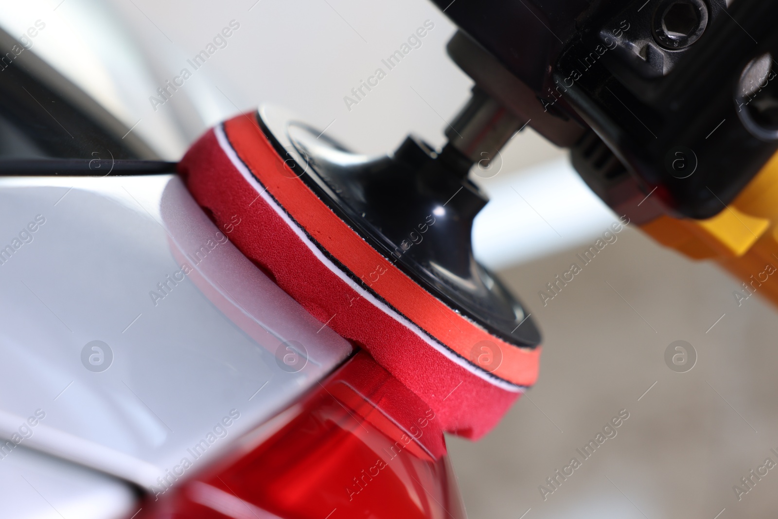 Photo of Man polishing car with orbital polisher indoors, closeup