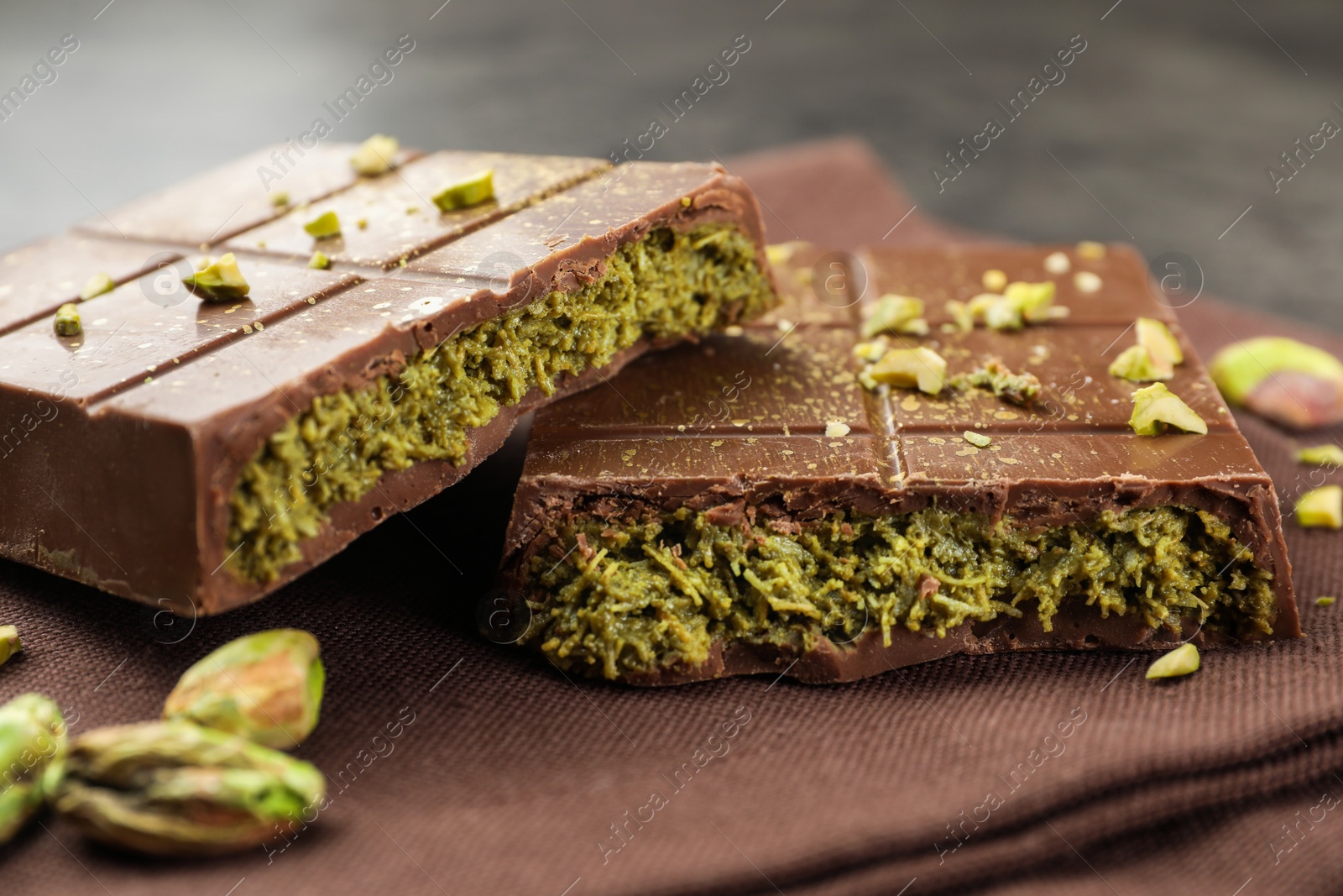 Photo of Pieces of tasty Dubai chocolate bar with pistachios and knafeh on table, closeup