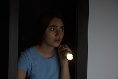 Photo of Fear of darkness. Scared young woman with flashlight indoors at night