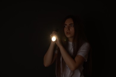 Photo of Fear of darkness. Scared young woman with flashlight indoors at night