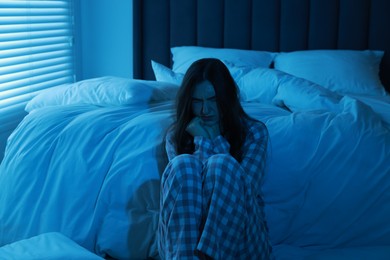 Fear of darkness. Scared young woman in bedroom at night