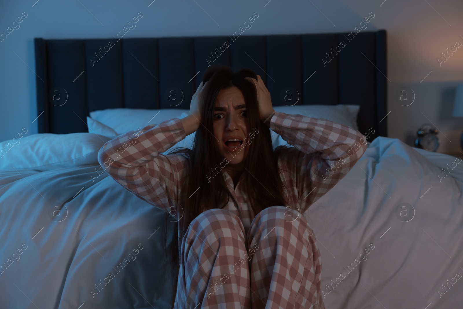 Photo of Fear of darkness. Scared young woman in bedroom at night