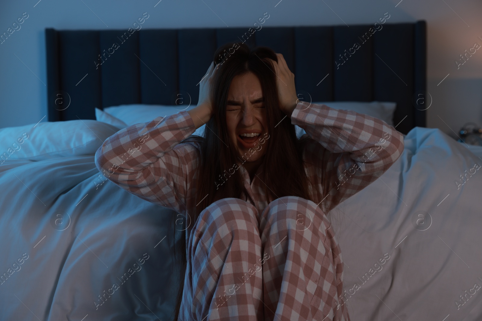 Photo of Fear of darkness. Scared young woman in bedroom at night