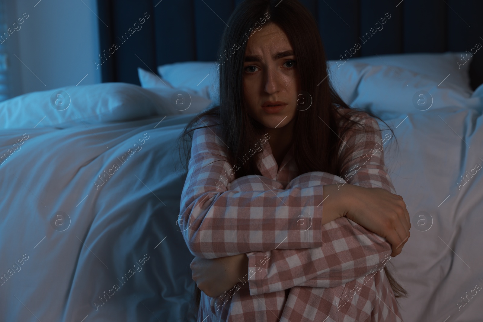 Photo of Fear of darkness. Scared young woman in bedroom at night