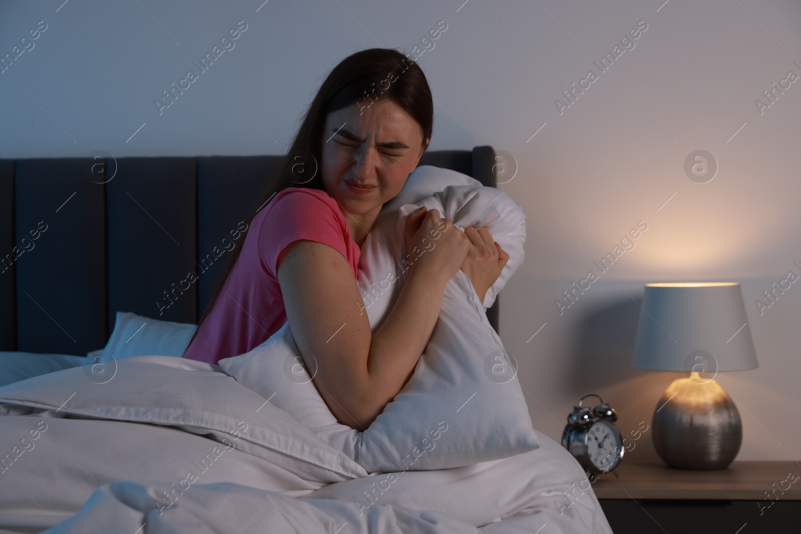 Photo of Fear of darkness. Scared young woman on bed in room at night