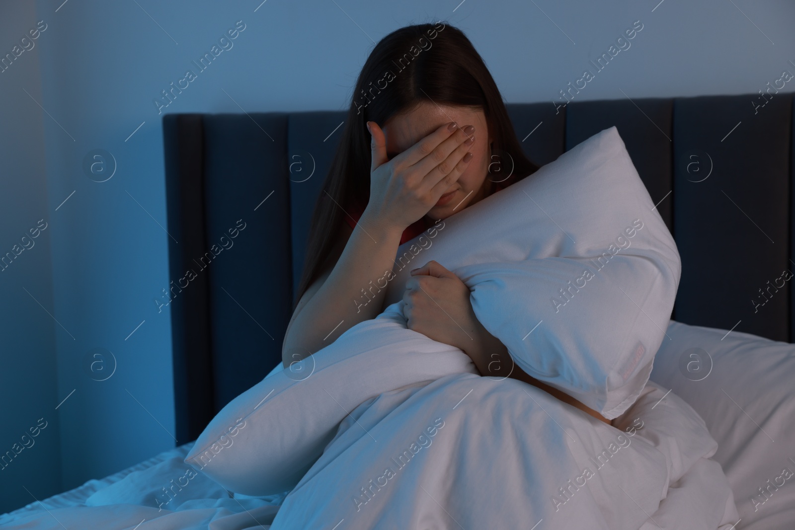 Photo of Fear of darkness. Scared young woman on bed in room at night