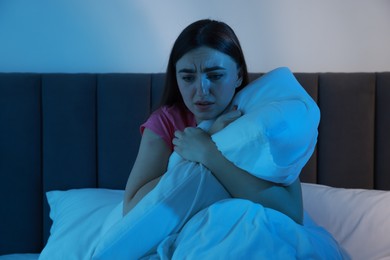 Photo of Fear of darkness. Scared young woman on bed in room at night