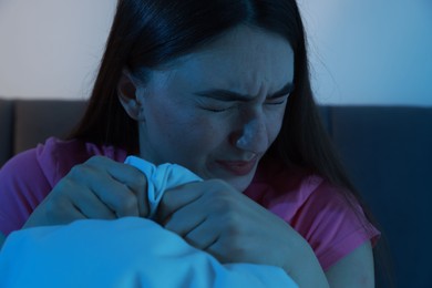 Photo of Fear of darkness. Scared young woman on bed in room at night