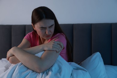 Photo of Fear of darkness. Scared young woman on bed in room at night