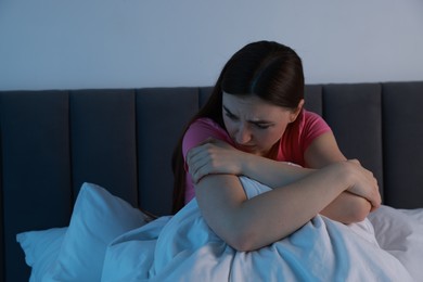 Photo of Fear of darkness. Scared young woman on bed in room at night