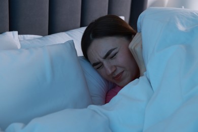 Photo of Fear of darkness. Scared young woman lying on bed in room at night