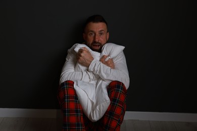 Photo of Fear of darkness. Scared man hugging pillow indoors at night