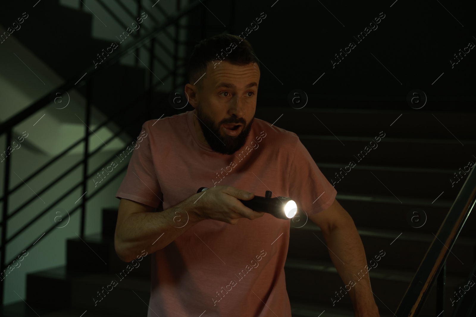 Photo of Fear of darkness. Scared man with flashlight indoors at night