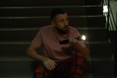 Photo of Fear of darkness. Scared man with flashlight indoors at night