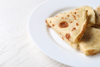 Photo of Delicious folded crepes on white wooden table, closeup. Space for text