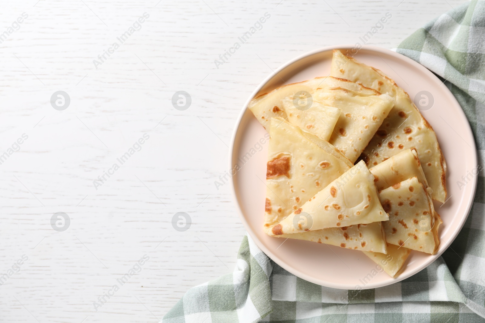 Photo of Delicious folded crepes on white wooden table, top view. Space for text