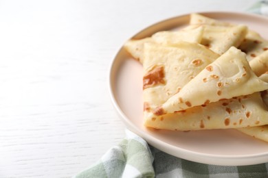 Photo of Delicious folded crepes on white wooden table, closeup. Space for text