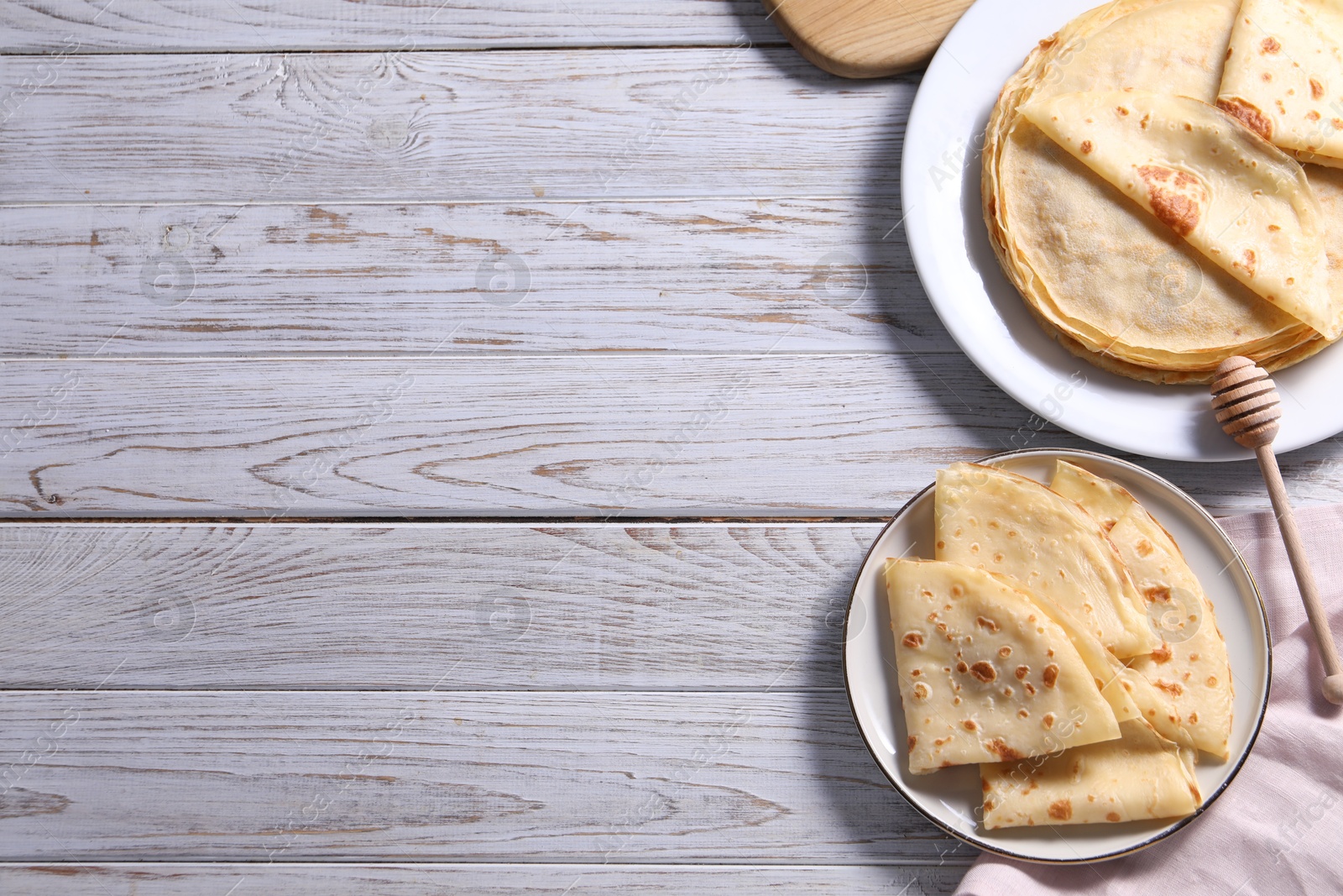 Photo of Delicious folded crepes on wooden rustic table, flat lay. Space for text