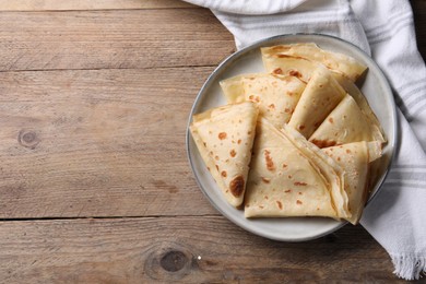 Photo of Delicious folded crepes on wooden table, top view. Space for text