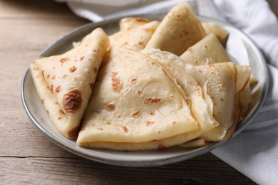 Photo of Delicious folded crepes on wooden table, closeup