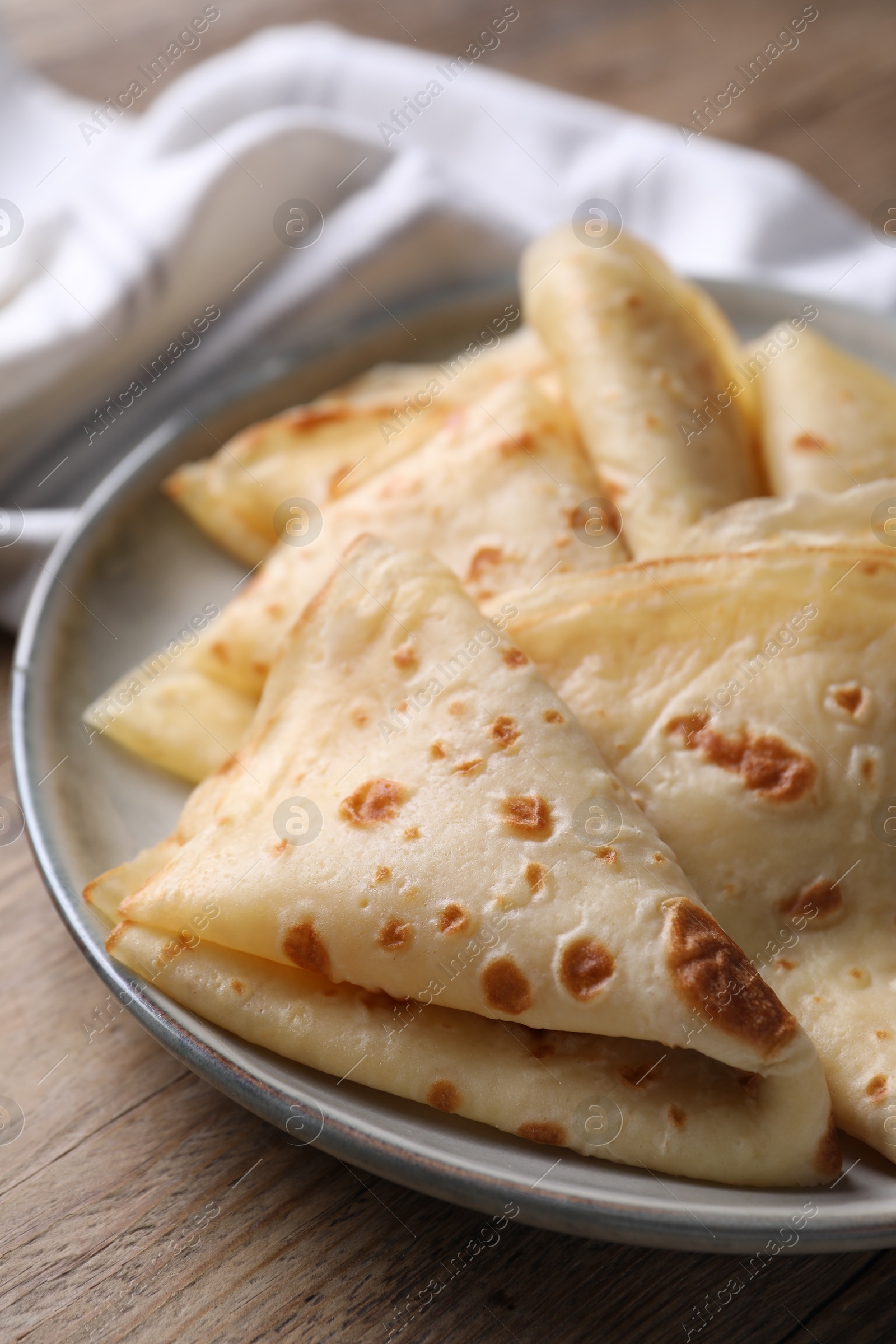 Photo of Delicious folded crepes on wooden table, closeup