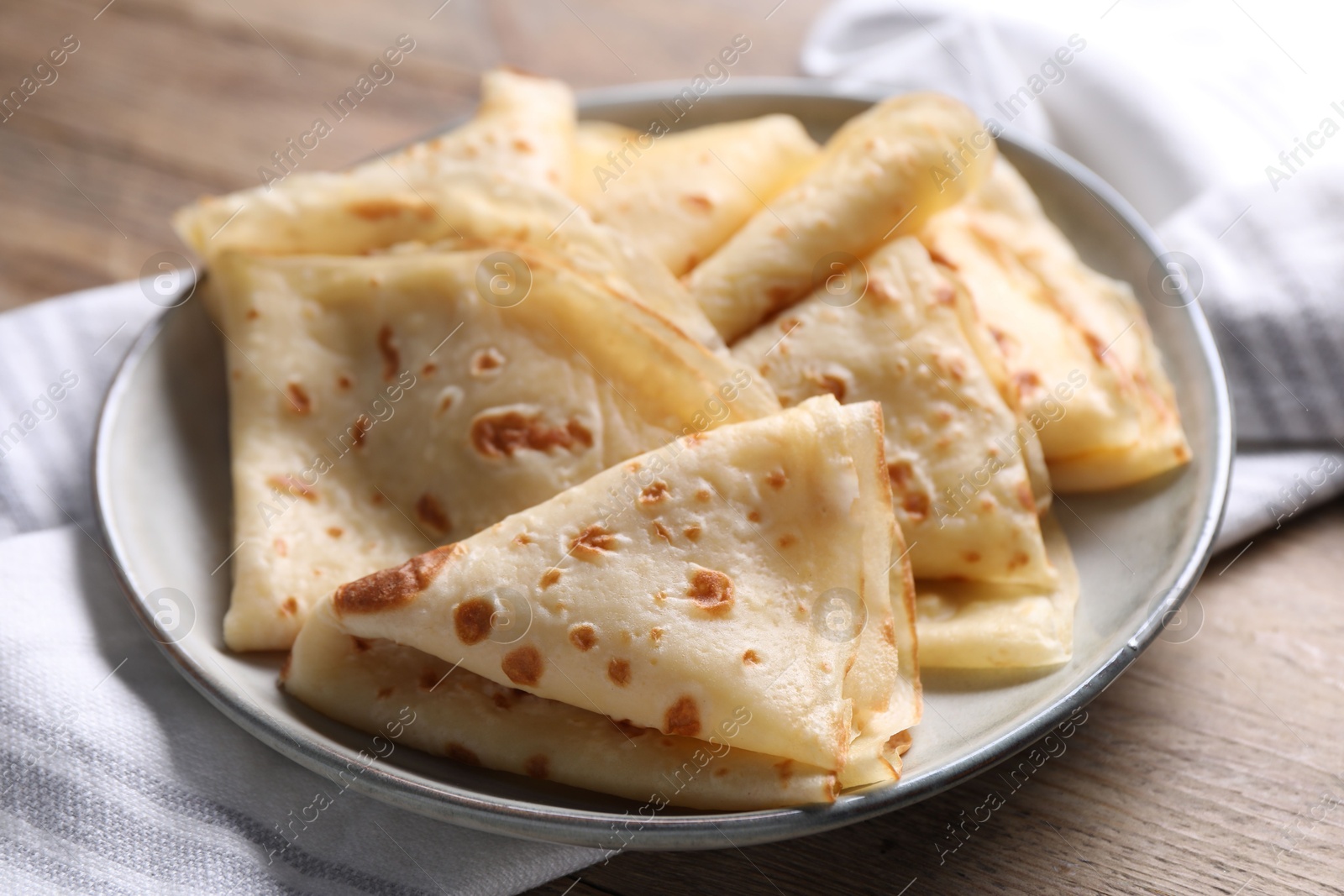 Photo of Delicious folded crepes on wooden table, closeup