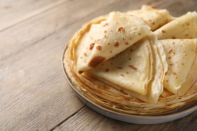 Photo of Delicious folded crepes on wooden table, closeup. Space for text