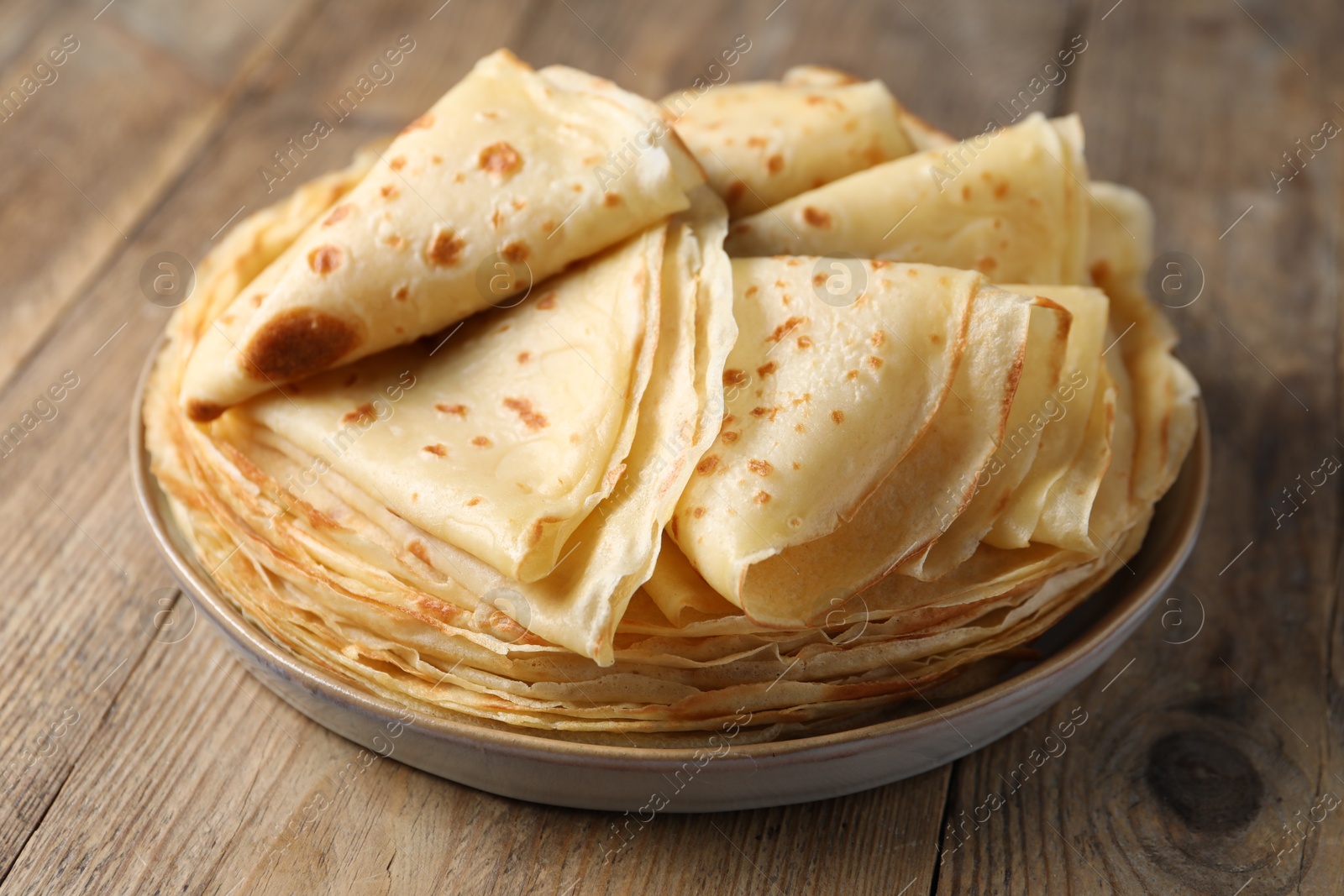 Photo of Delicious folded crepes on wooden table, closeup