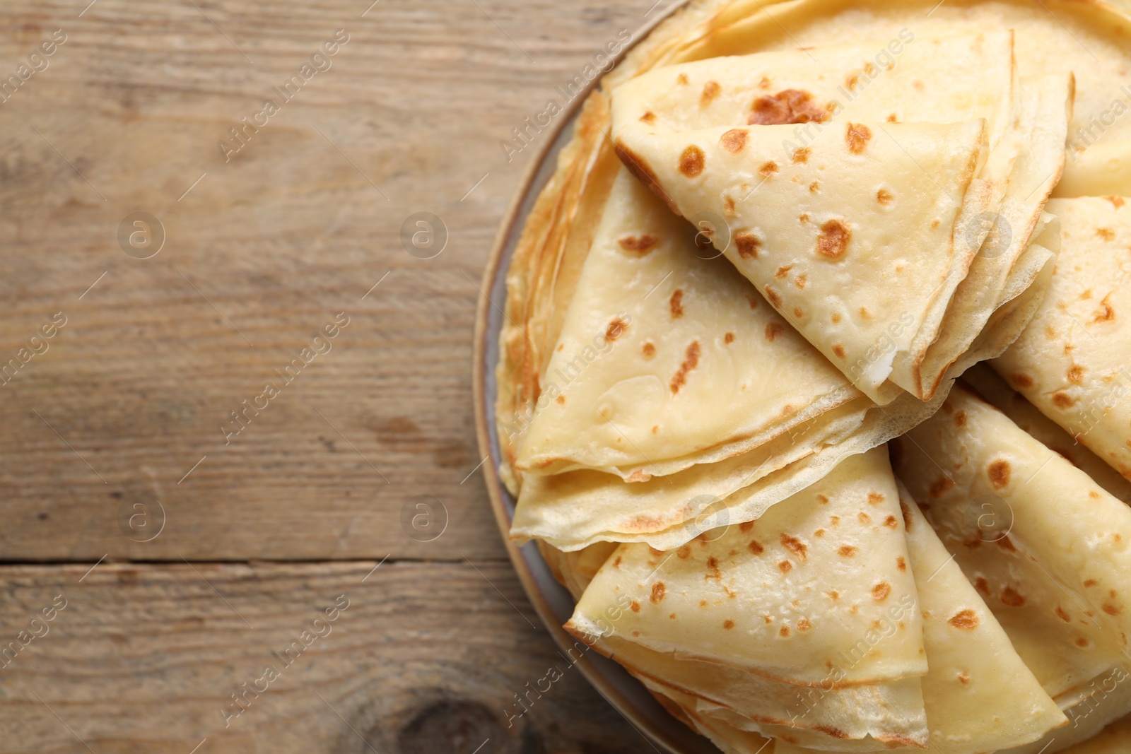 Photo of Delicious folded crepes on wooden table, closeup. Space for text