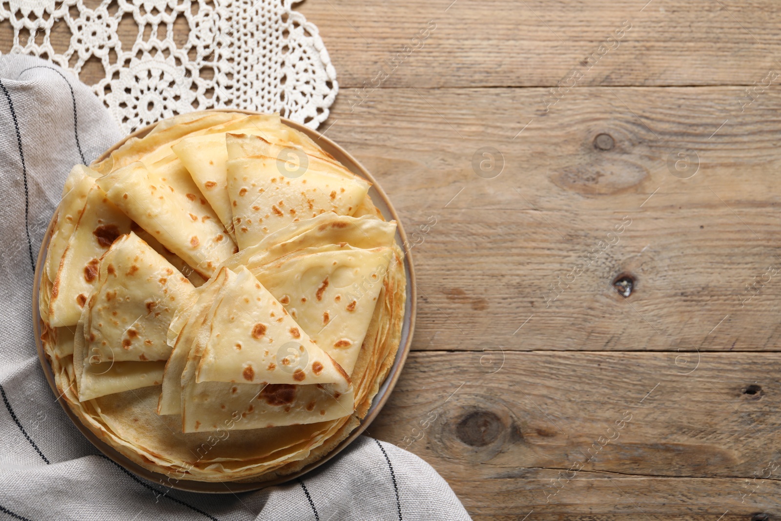 Photo of Delicious folded crepes on wooden table, top view. Space for text