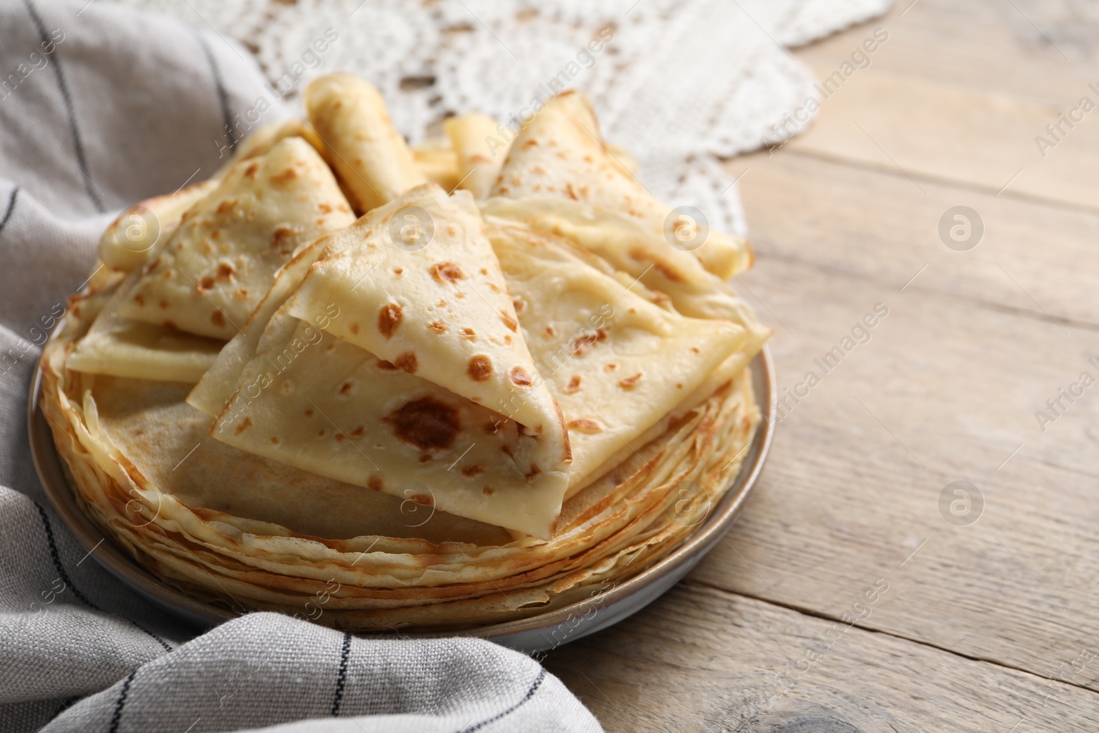 Photo of Delicious folded crepes on wooden table, closeup. Space for text