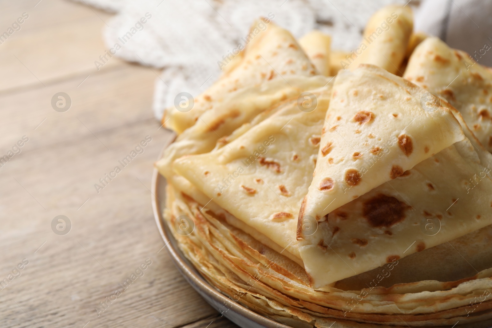 Photo of Delicious folded crepes on wooden table, closeup. Space for text