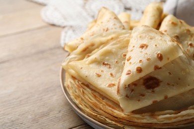 Photo of Delicious folded crepes on wooden table, closeup. Space for text