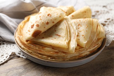 Photo of Delicious folded crepes on wooden table, closeup