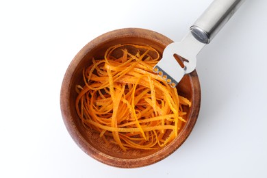 Photo of Fresh orange zest in bowl and zester tool isolated on white, top view