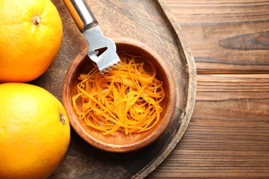 Photo of Orange zest, zester tool and fresh fruits on wooden table, top view. Space for text